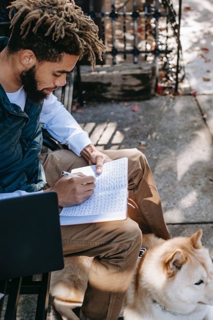 ethnic man sitting with dog on bench