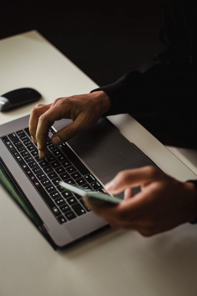 crop faceless man using laptop and smartphone in office