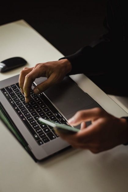 crop faceless man using laptop and smartphone in office